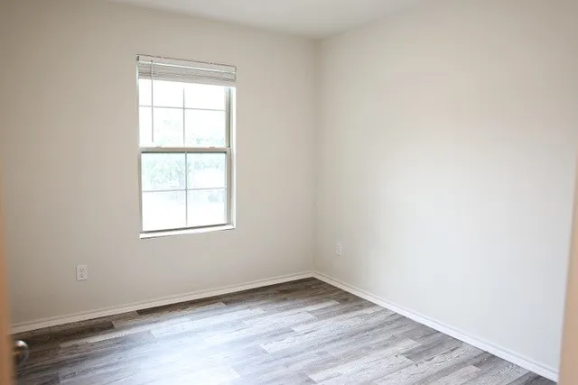 Neutral wall finishes and wood-finish flooring with white baseboards