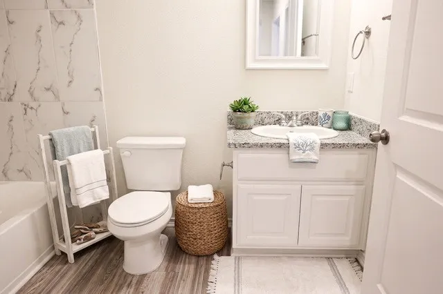 Bathroom featuring a white vanity with a granite countertop, undermount sink, and chrome faucet