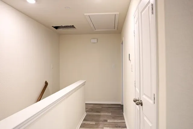 Second-story hallway featuring wood-finish flooring, recessed lighting, and a white paneled door