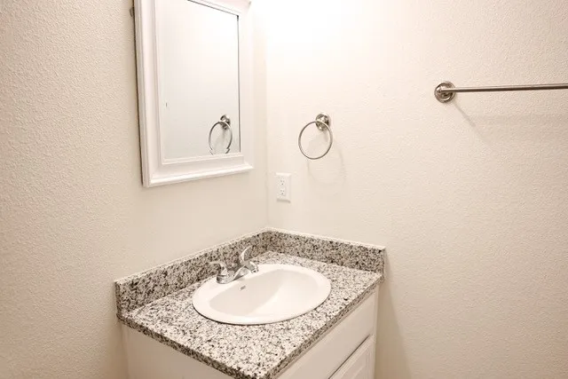 Bathroom vanity with a white cabinet, speckled countertop, and an oval undermount sink