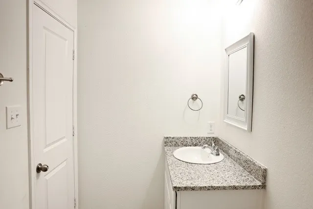 Bathroom vanity featuring a speckled countertop, undermount sink, and chrome faucet