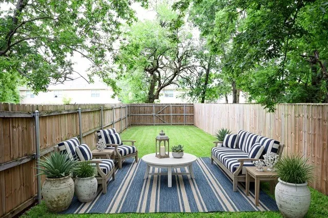 Private backyard featuring a wooden privacy fence, manicured lawn, and mature trees