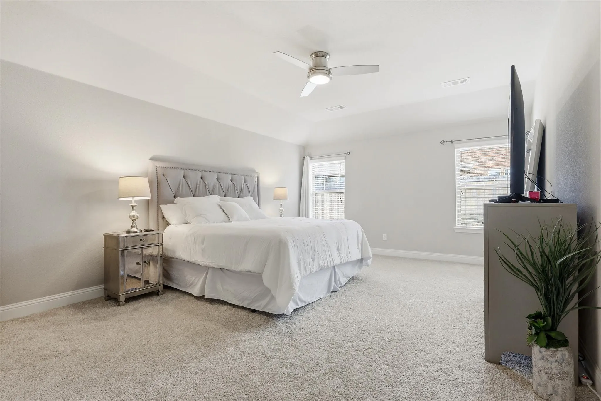Primary bdrm featuring light-toned walls, plush carpeting, and a ceiling fan with integrated lighting