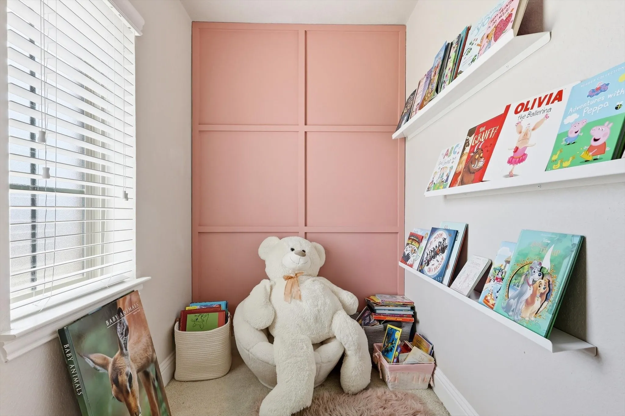 Reading nook off bedroom #3 w/ paneled accent wall, white window blinds, and built-in floating book shelves
