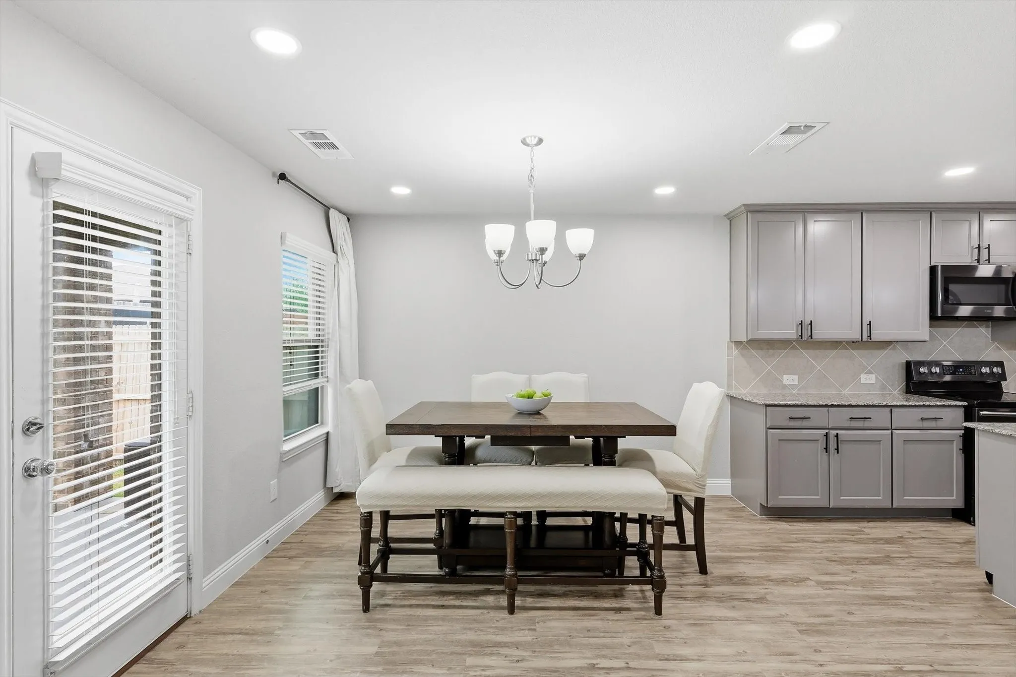 Open-concept dining area featuring wood-finish flooring, recessed lighting, and a modern chandelier
