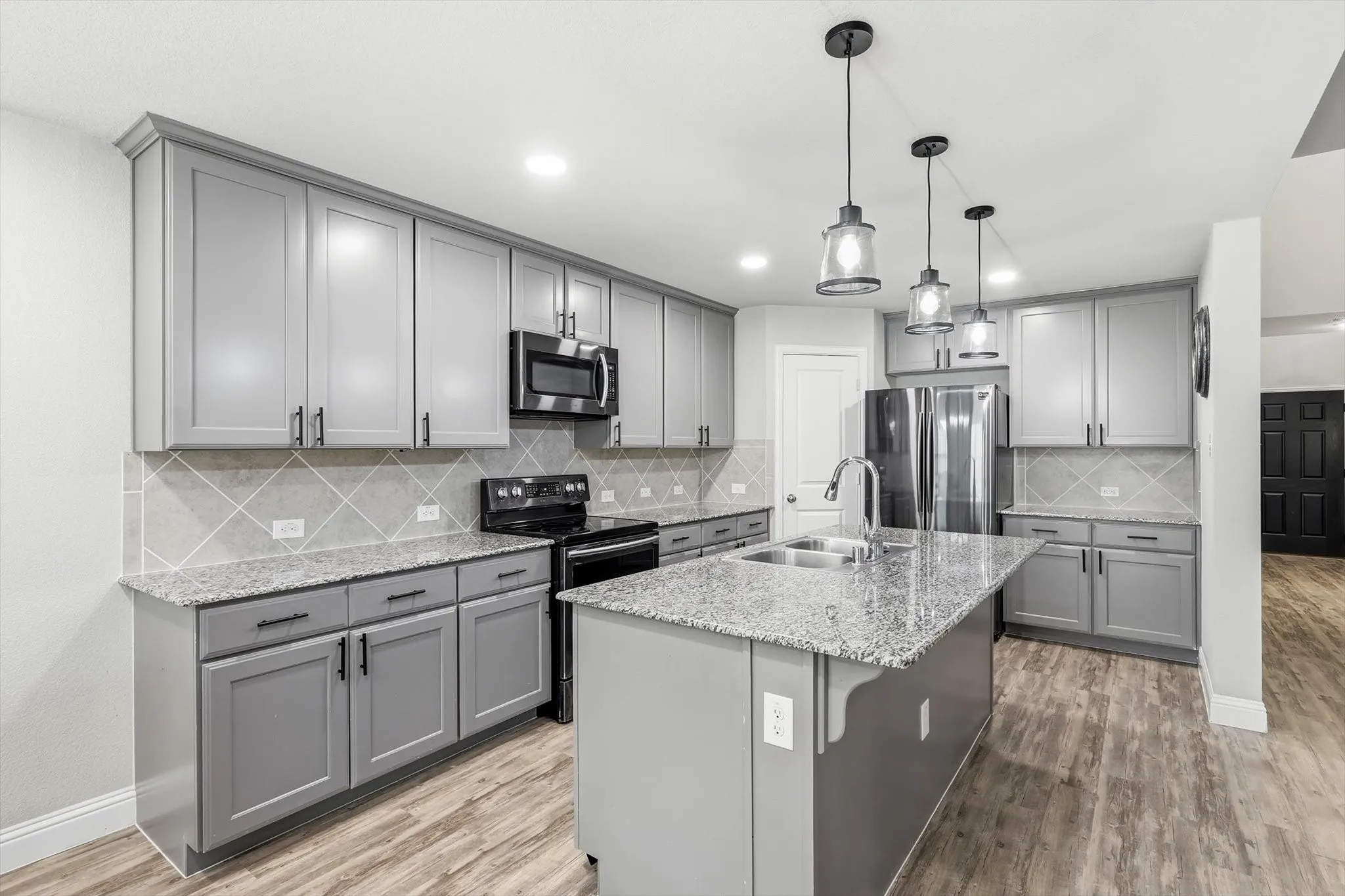 Kitchen featuring grey cabinetry, granite countertops, and stainless steel appliances including a microwave and range