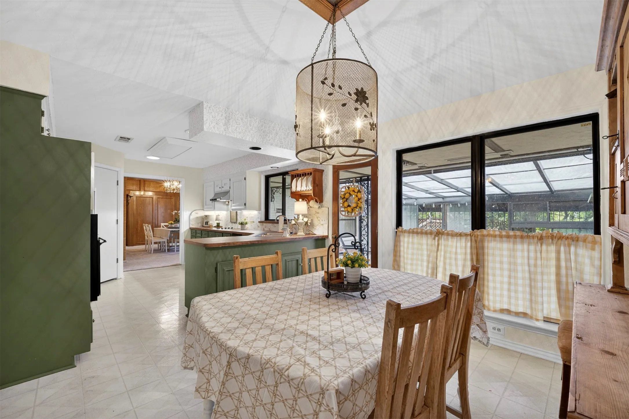 Dining area featuring a decorative chandelier with candelabra-style lights, a tall vaulted ceiling, large windows, and tile flooring