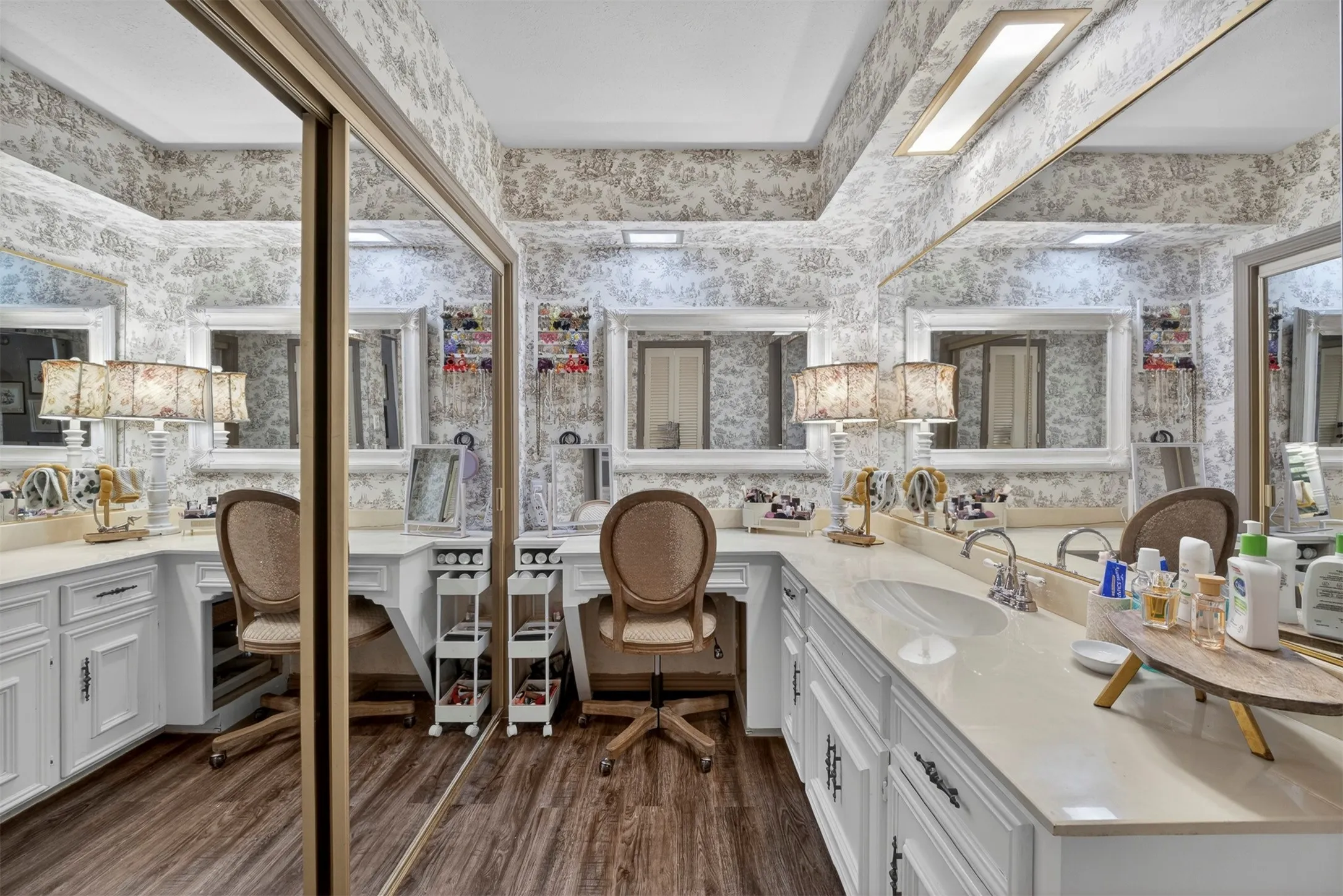 Expansive vanity space featuring wood-finish flooring and patterned wall covering