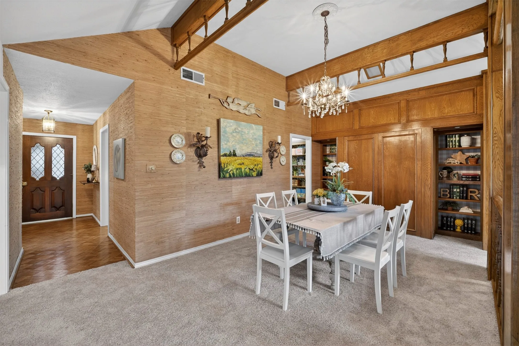 Dining area featuring vaulted ceilings, wood-finish flooring, built-in shelving, and a chandelier
