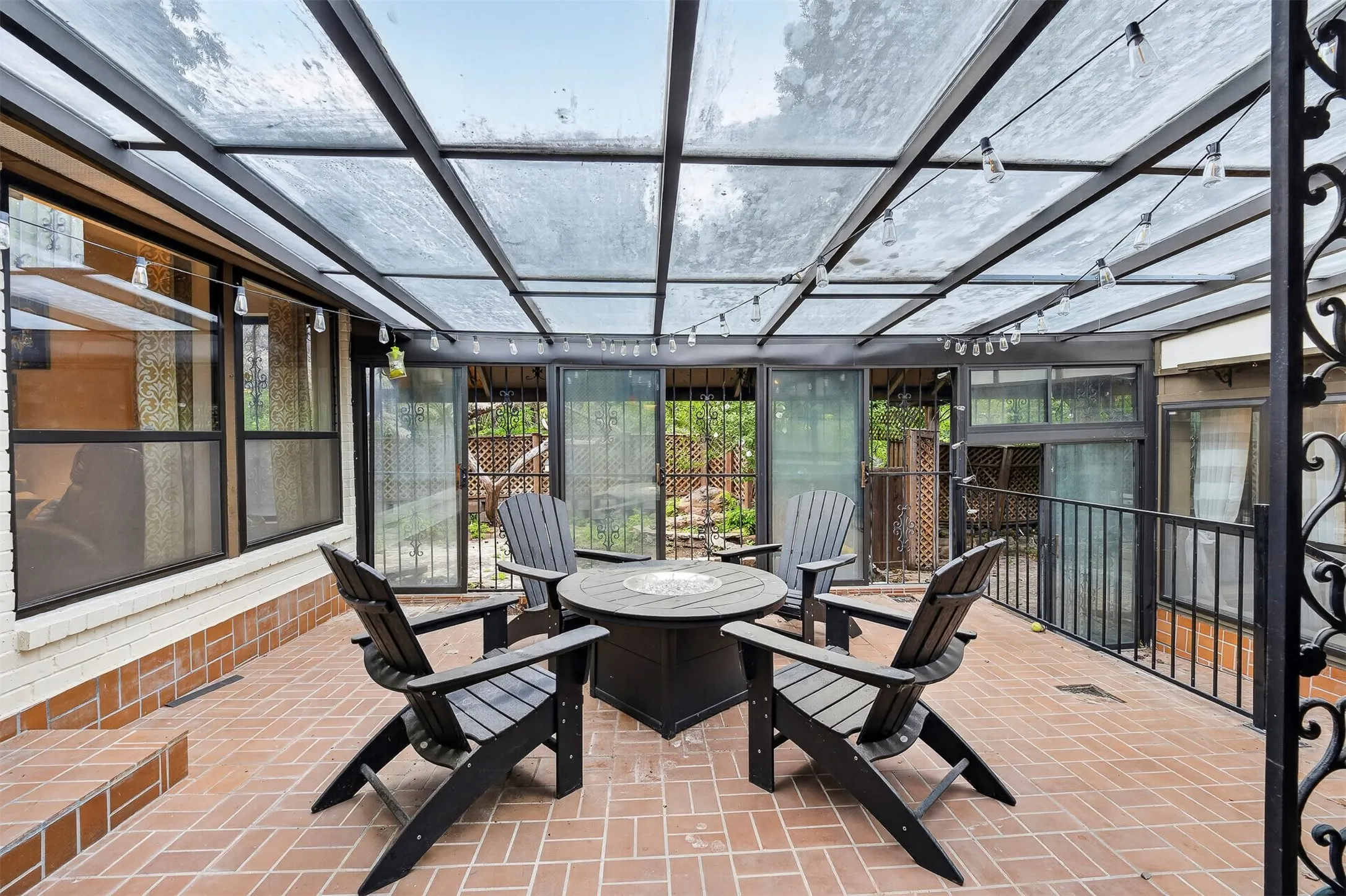 Covered patio featuring a clear panel roof, string lighting, and brick paver flooring