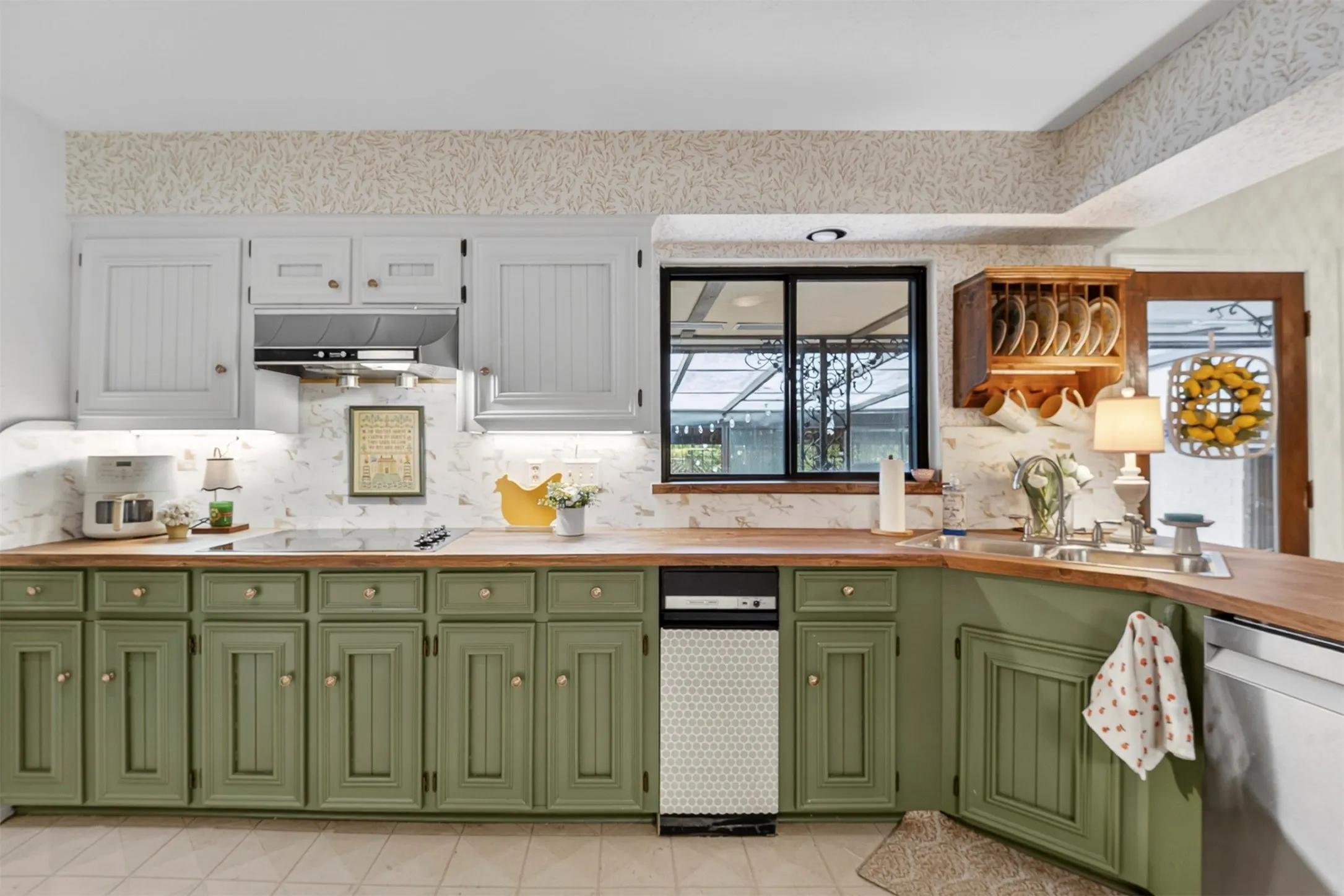 Open-concept kitchen featuring two-tone cabinetry with green base cabinets and light upper cabinets, complementing wood-finish countertops