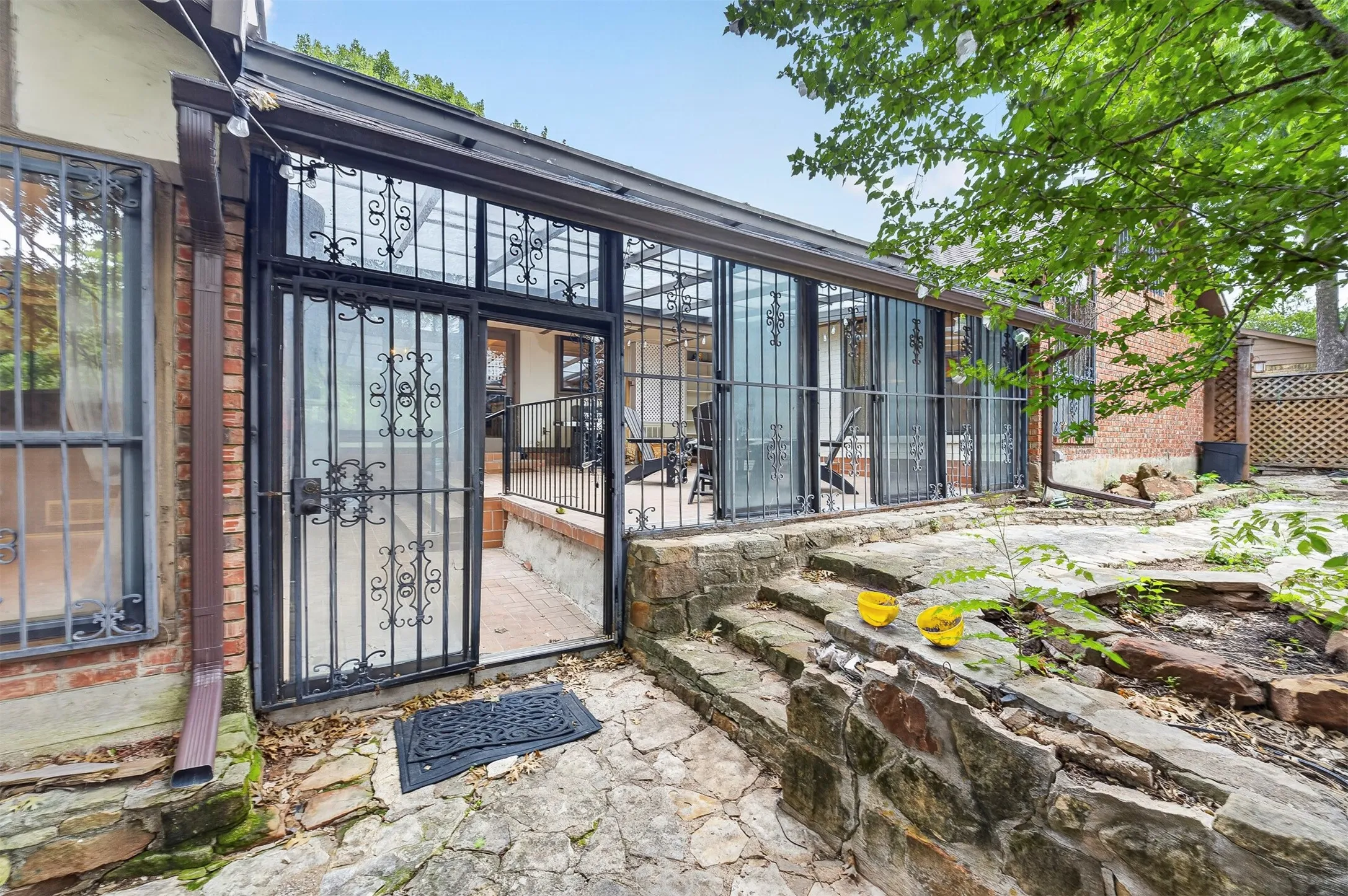Enclosed patio featuring wrought iron security doors and a stone patio with tiered stone steps