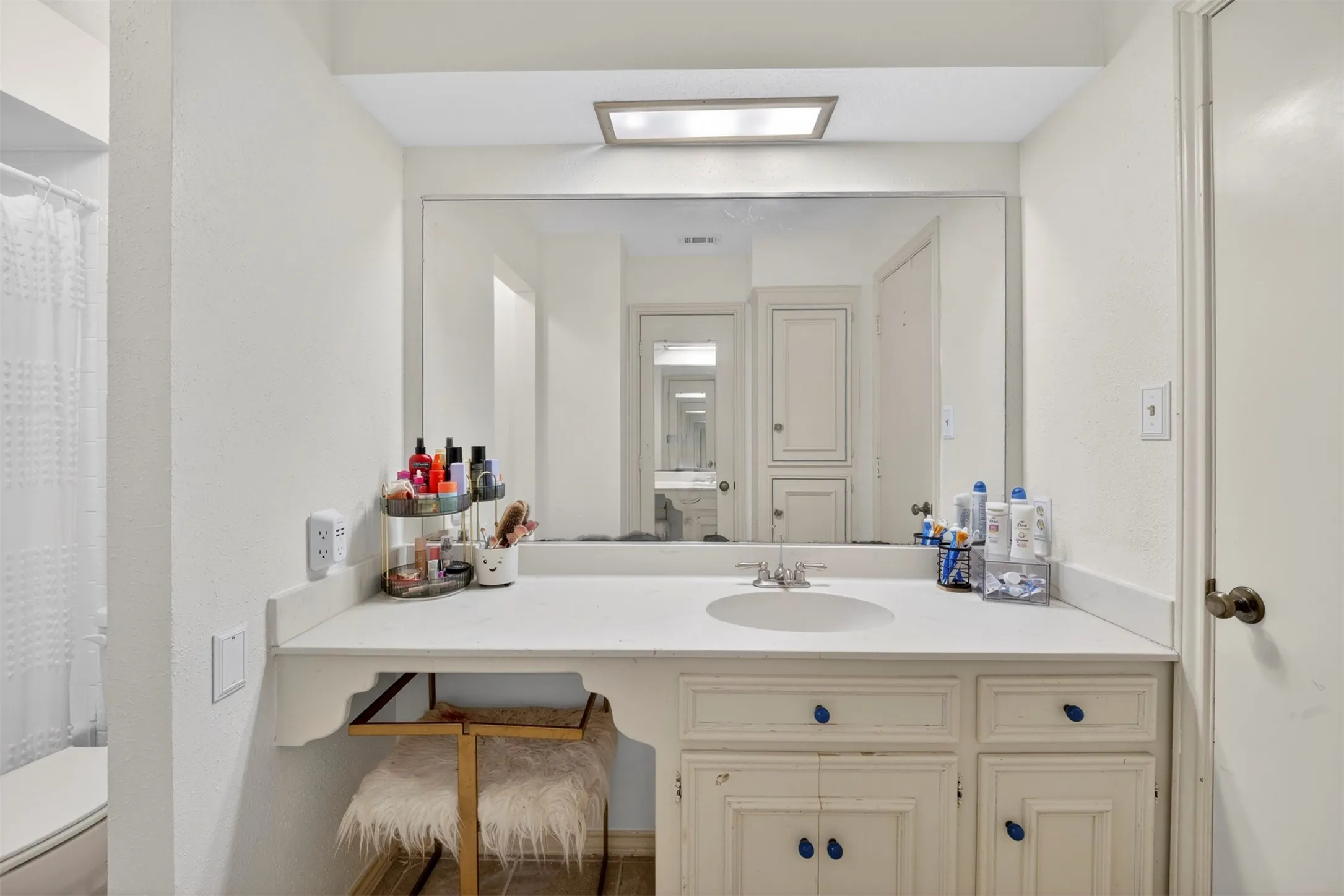 Bathroom vanity featuring a single basin, integrated countertop, and lower cabinetry with blue knob accents