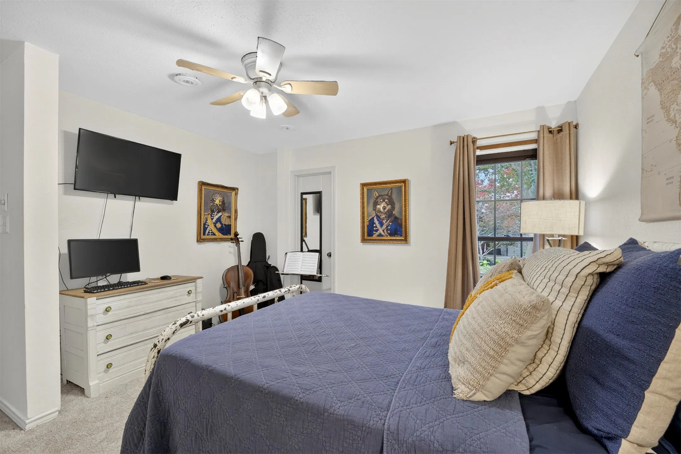 Carpeted room featuring a ceiling fan with light fixture, a window with curtain rods, and a white door frame