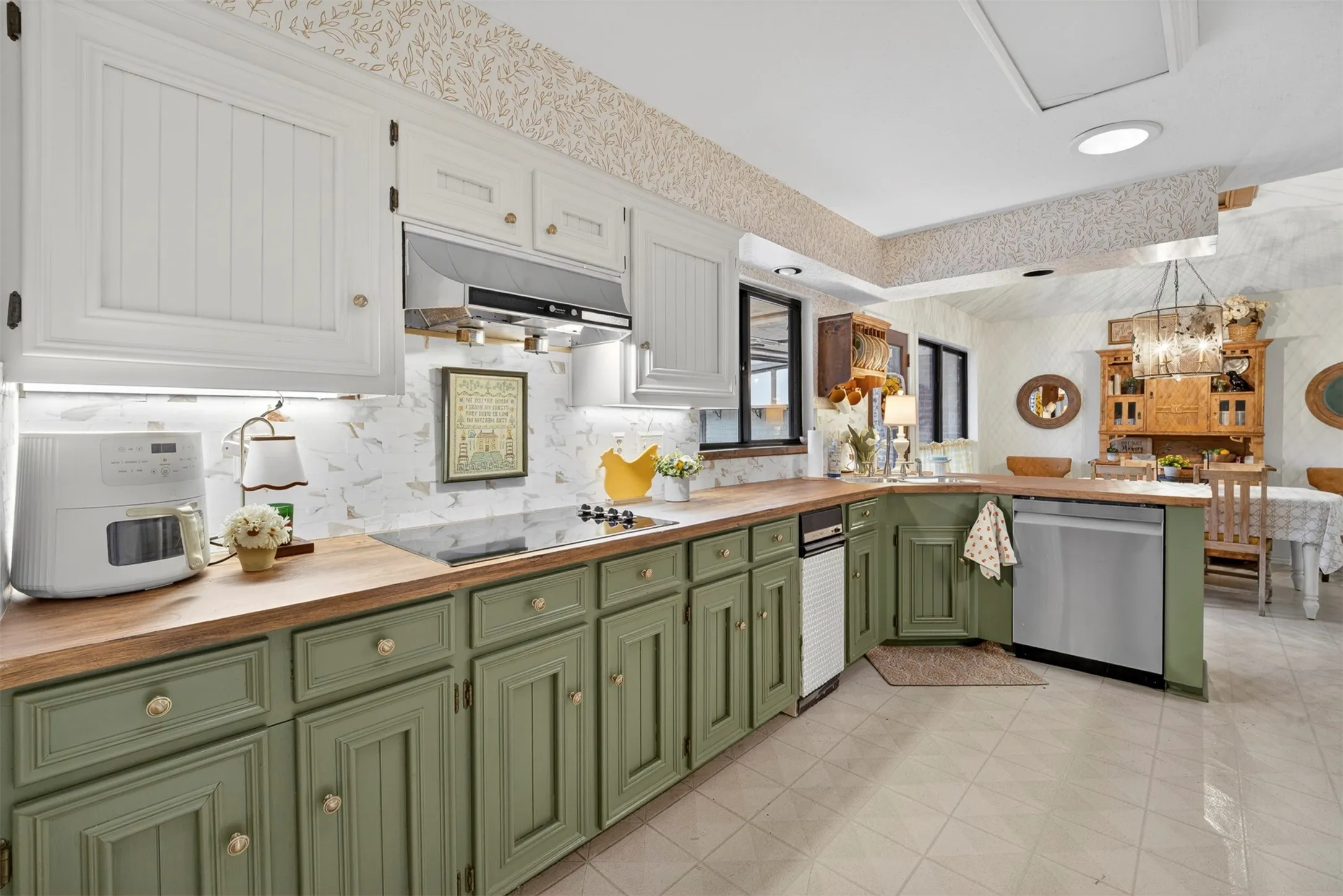 Spacious kitchen featuring two-tone cabinetry with white upper and green lower cabinets, wood-finish countertops, and a built-in electric cooktop