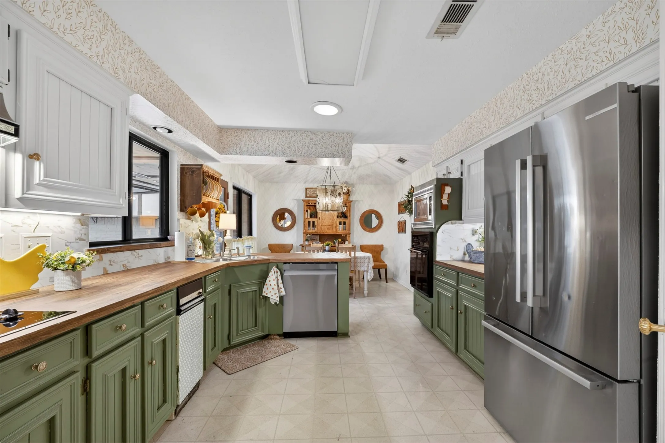 Kitchen featuring custom cabinetry, wood-finish countertops, stainless steel appliances, and tile flooring
