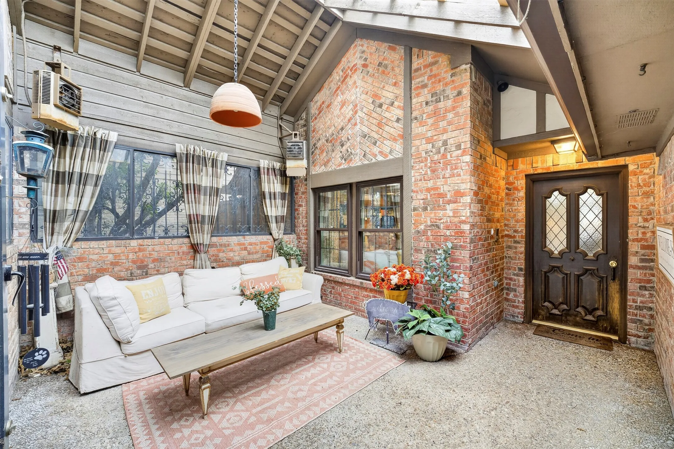 Covered entryway featuring brick facade and a dark wood front door with leaded glass inserts
