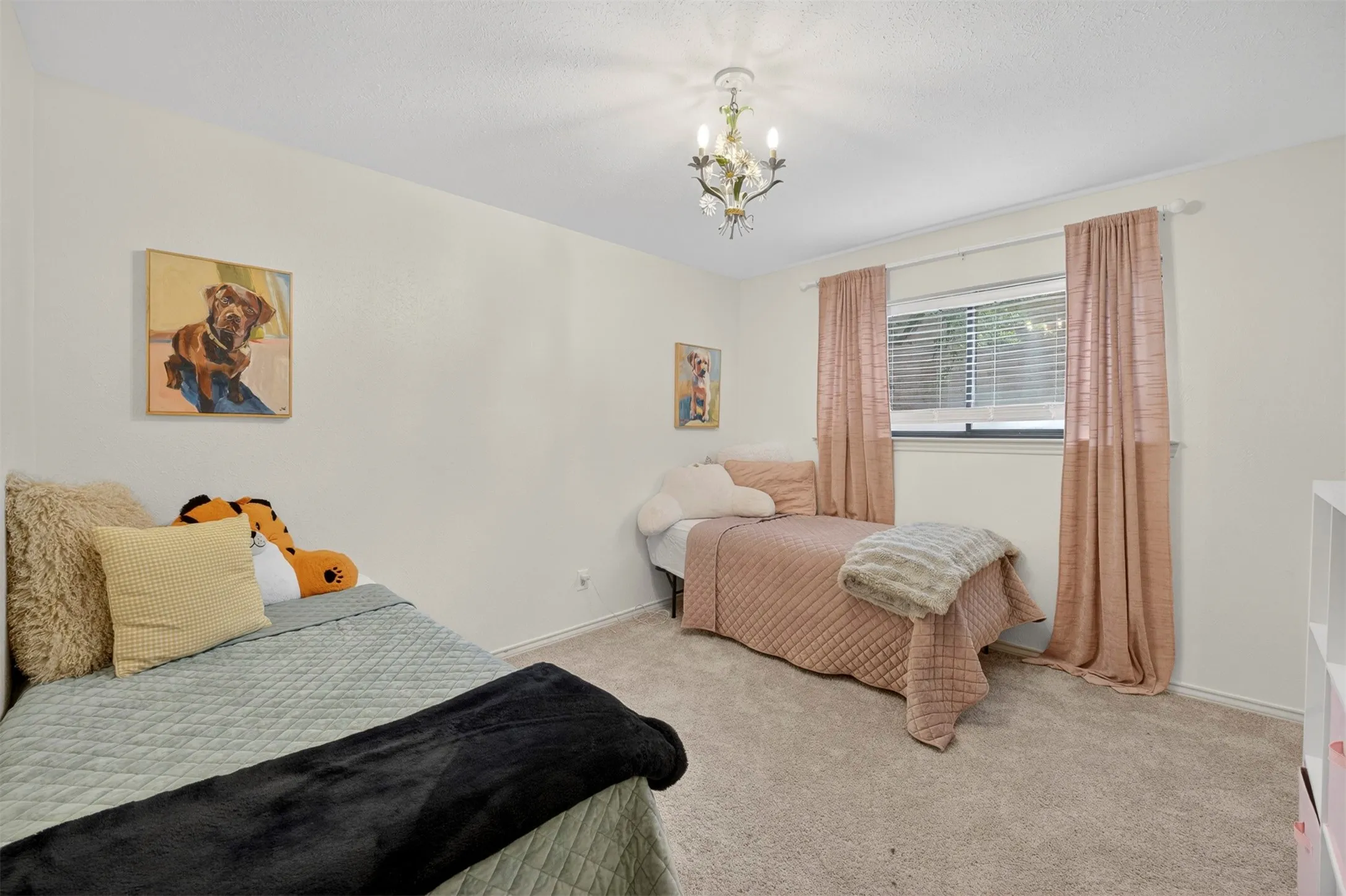 Carpeted bedroom featuring a central chandelier, a window with horizontal blinds, and neutral-toned walls