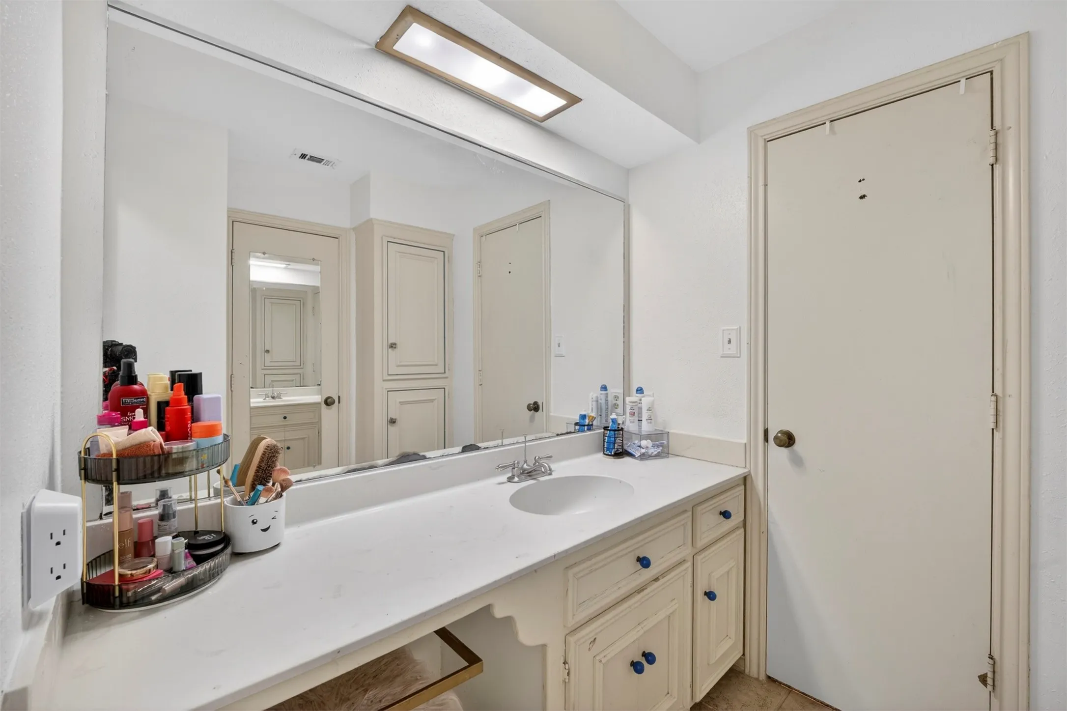 Bathroom vanity featuring a single basin sink and white countertop
