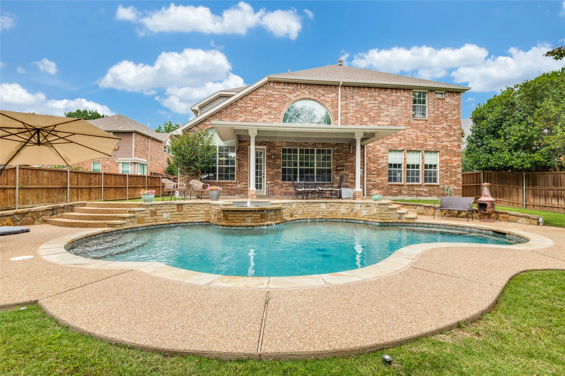 Expansive backyard oasis featuring a freeform pool with stone coping and an integrated spa