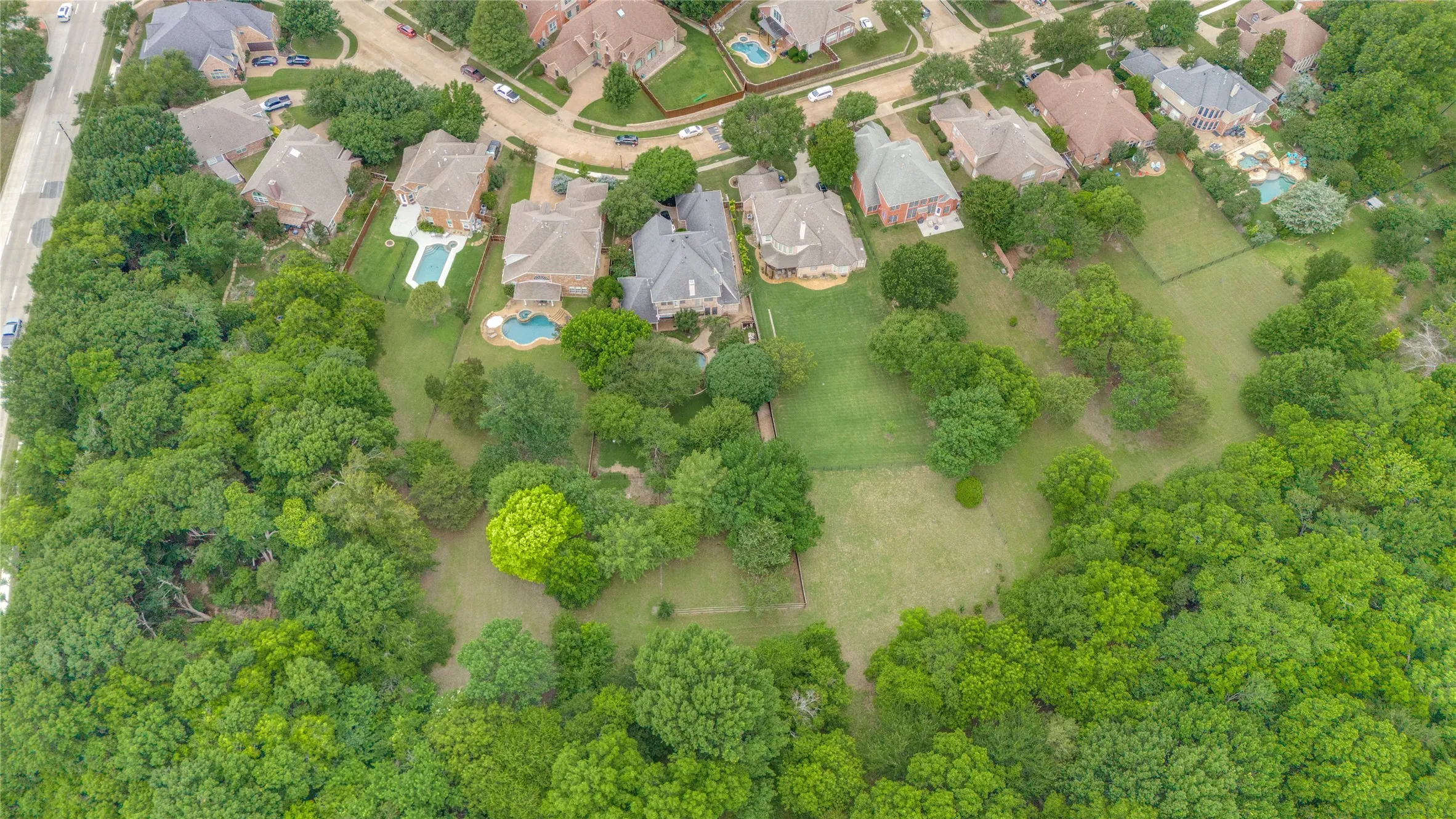 Expansive green space featuring a grass-covered field surrounded by mature trees
