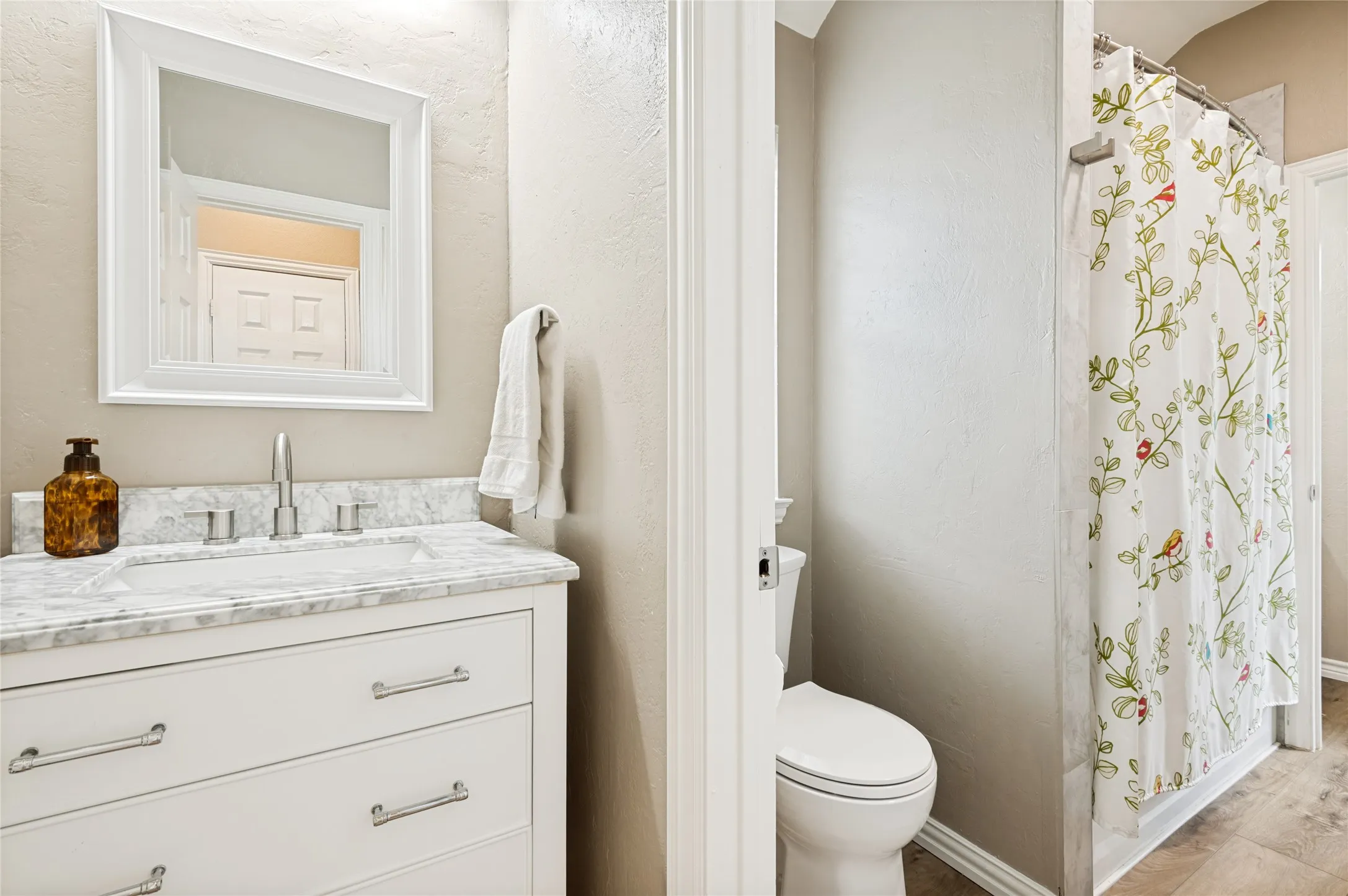 Bathroom featuring a white vanity with an undermount sink, a stone-finish countertop, and brushed nickel hardware