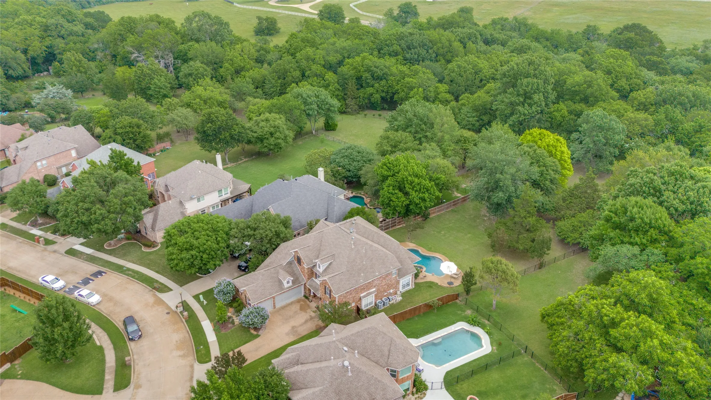 Aerial perspective showcasing multiple properties, each featuring a private swimming pool, mature landscaping, and fenced backyards