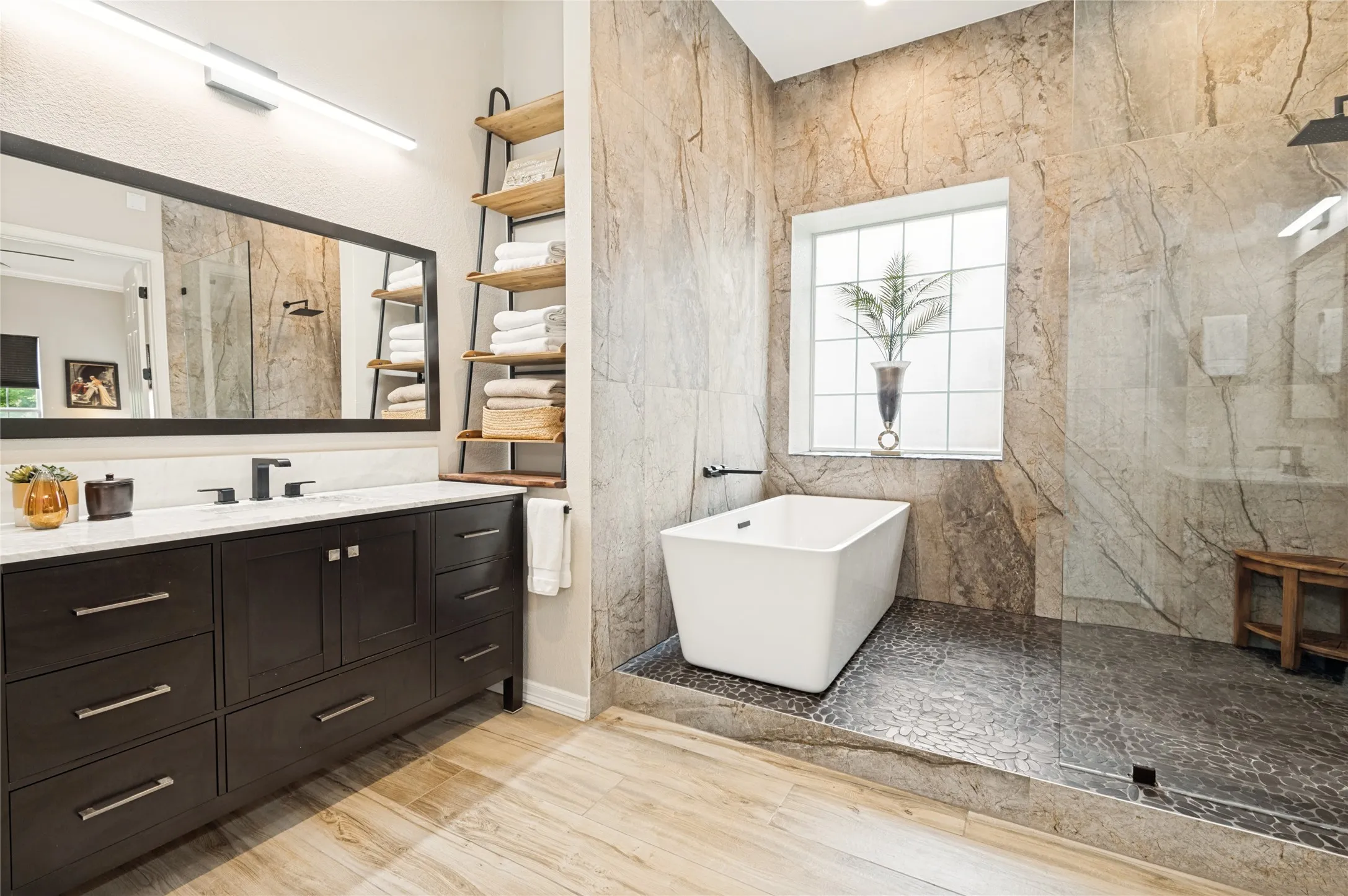 Bathroom featuring a freestanding soaking tub and a walk-in shower with stone tile walls