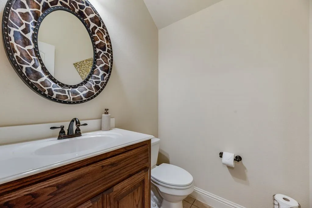 Wood-finish vanity with an integrated white sink and a bronze-finish faucet, adjacent to flex room or office