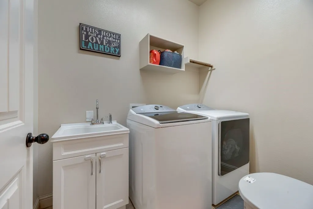 Utility room featuring a white vanity with an integrated sink, wall-mounted open shelving, and a hanging rod