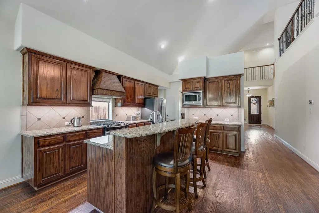 Kitchen featuring wood-finish cabinetry, granite countertops, and a tile backsplash