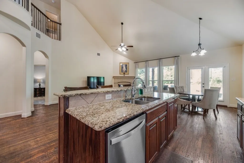 Kitchen island featuring granite countertops, a dual basin stainless steel sink, and an integrated dishwasher