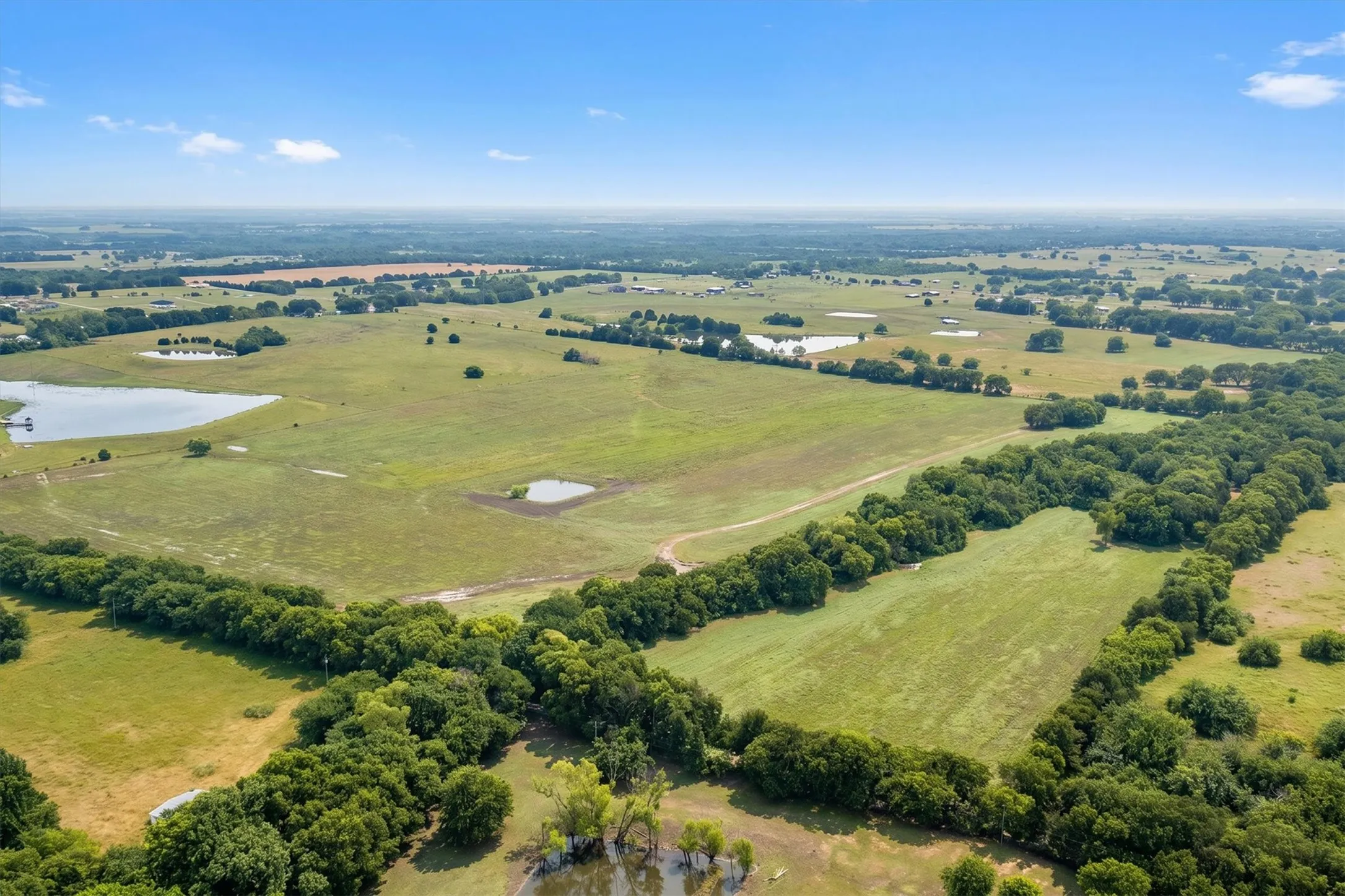 Expansive rural landscape featuring a mix of open pastures and dense tree lines
