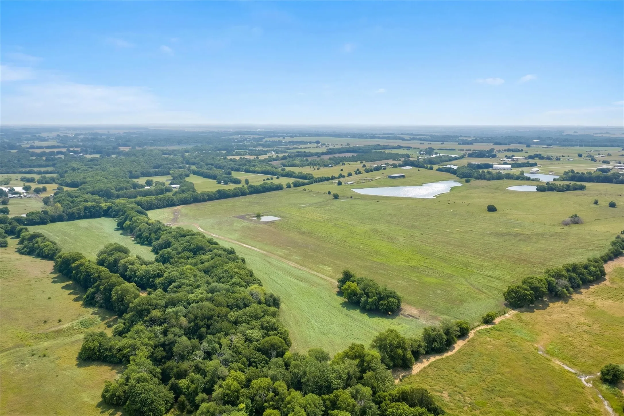 Expansive rural landscape featuring a mix of open fields and densely wooded areas