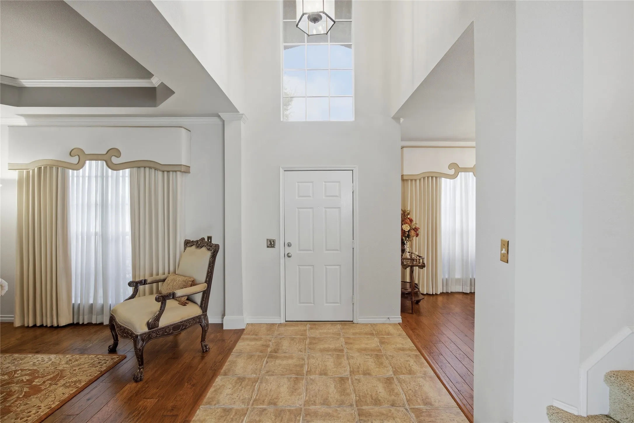 Foyer featuring a double-height ceiling, transom window, and a combination of tile and wood-finish flooring
