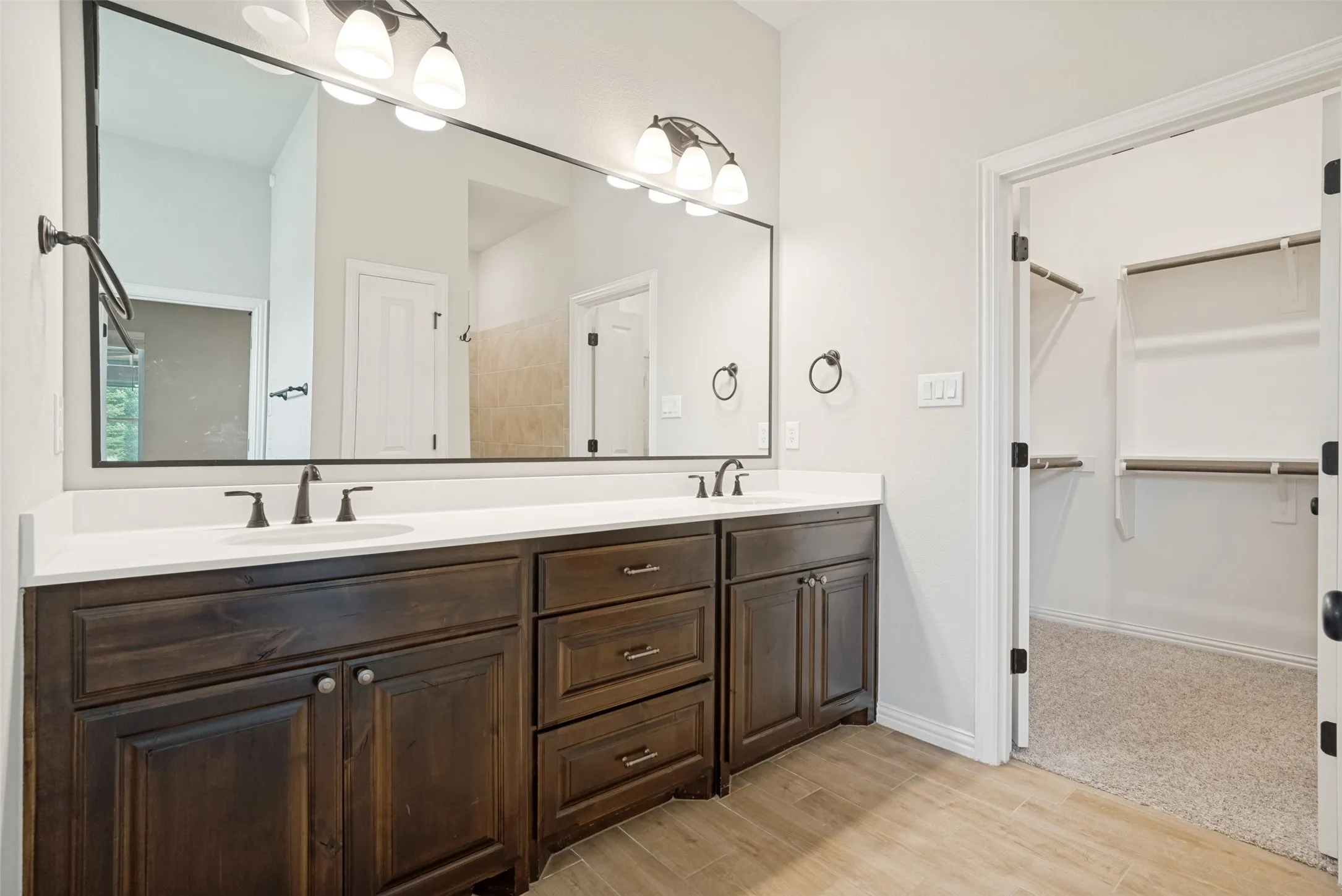 Bathroom featuring a dual vanity with dark wood cabinetry, white countertops, and black fixtures