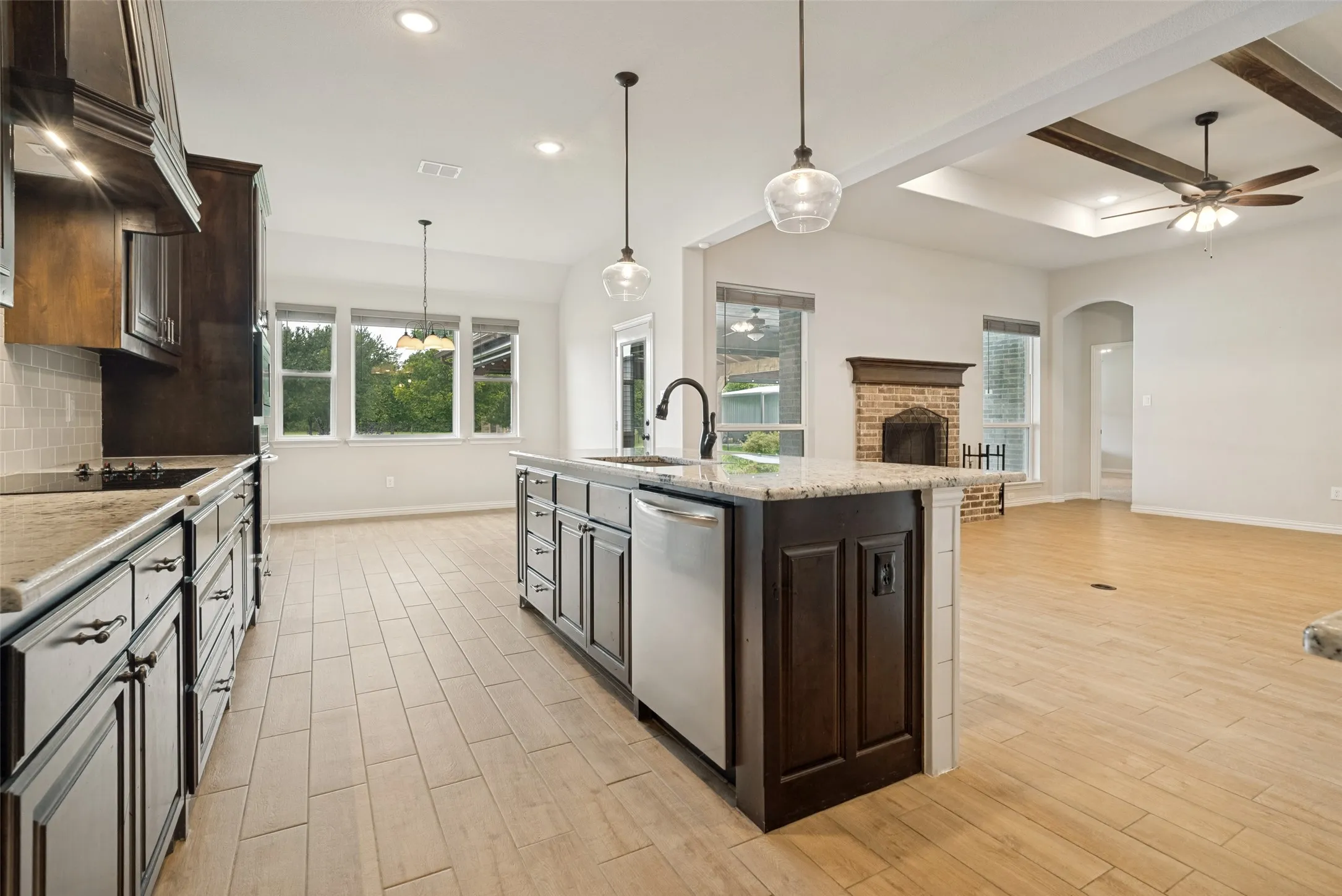 Expansive kitchen featuring a large island with sink, stainless steel dishwasher, and pendant lighting