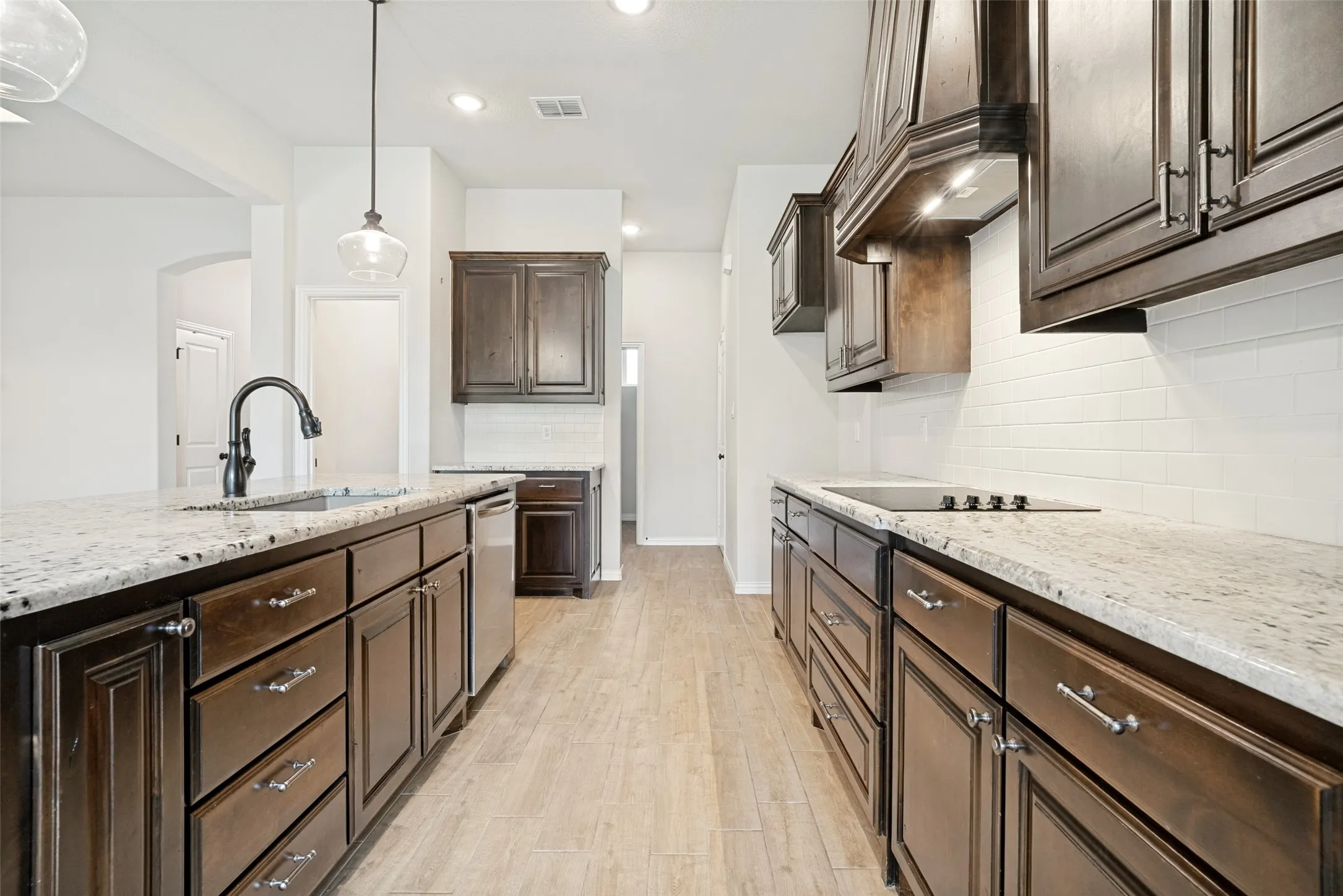 Contemporary kitchen featuring wood-finish cabinetry, light-toned countertops, and a subway tile backsplash