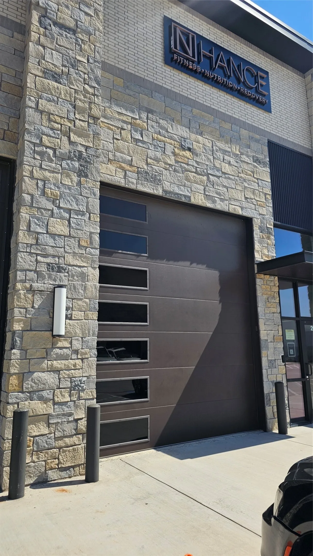 Stone veneer exterior with a modern garage door featuring horizontal window panels