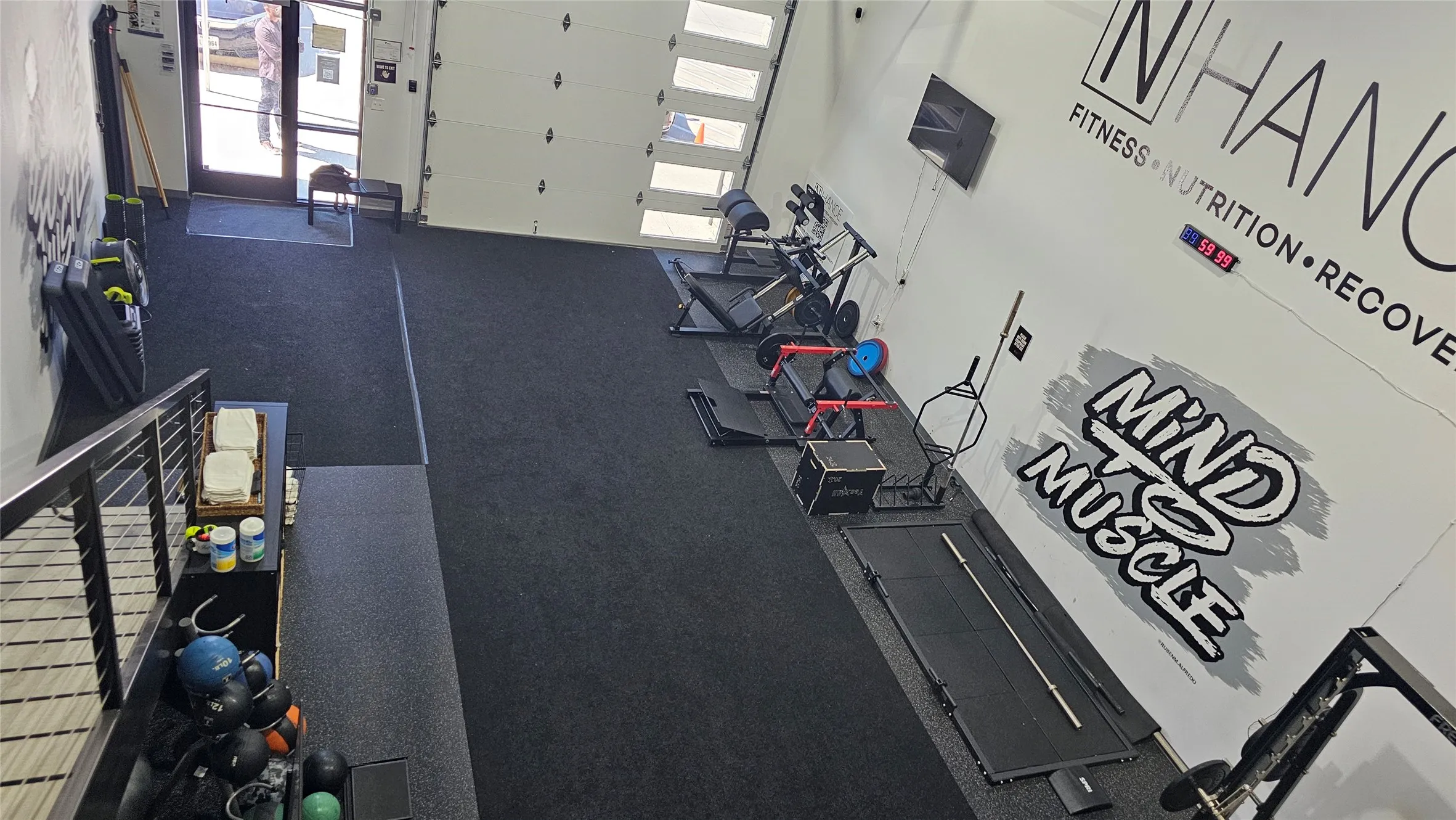 Spacious interior featuring a large overhead garage door, dark flooring, white walls, and a prominent wall-mounted digital display