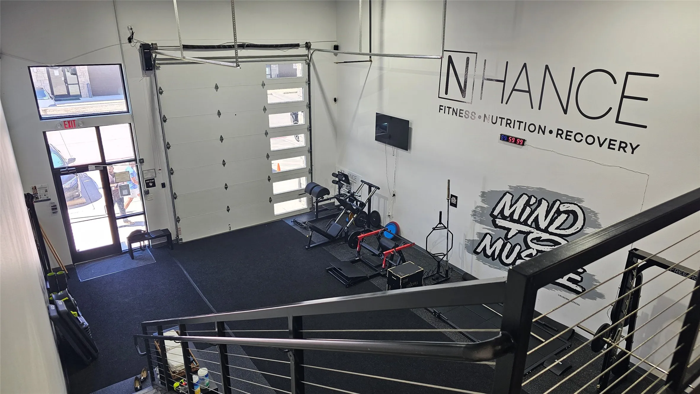 Spacious interior featuring high ceilings, a large roll-up garage door with frosted glass panels, durable black rubber flooring, and a glass-paneled entry door