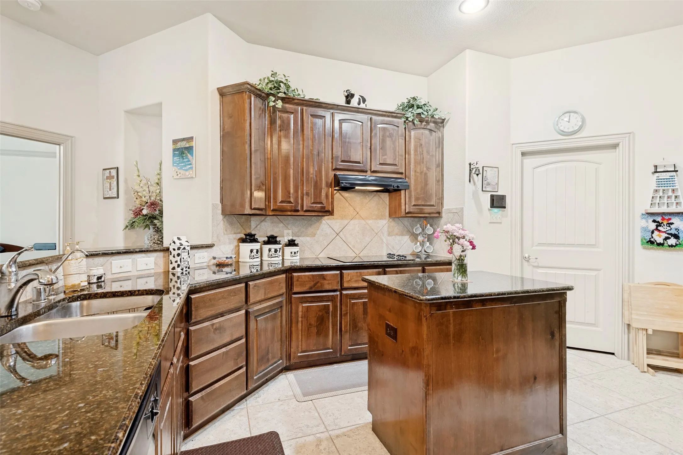 Features granite counters duel stainless sinks, stove top w tile backsplash view of door leading to large laundry room with fabulous pantry.