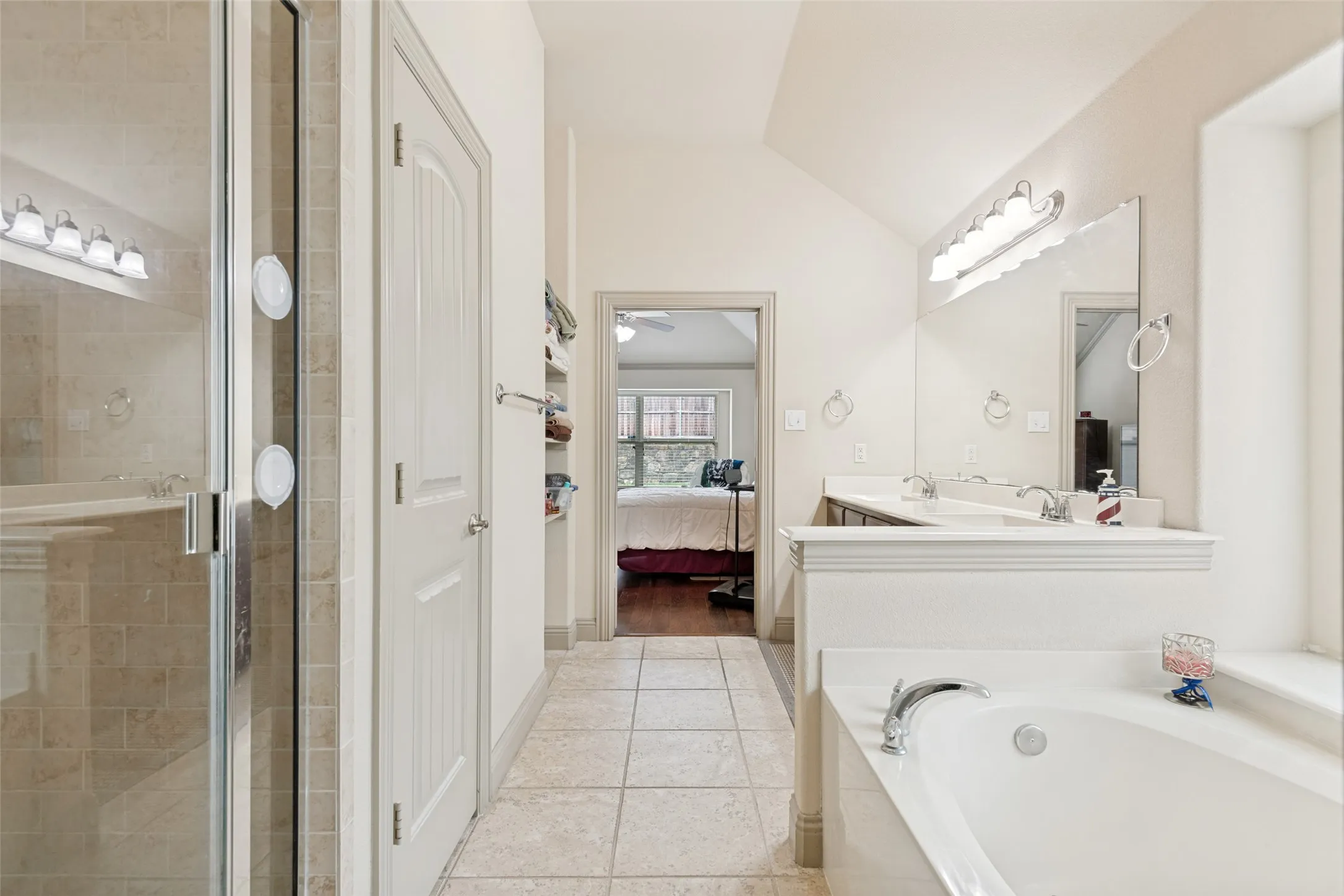 Master Bath features soaking tub window ledge shelf for decor, Tile shower with bench seat. Door to enclosed toilet area, wall shelves for Towels and accessories.