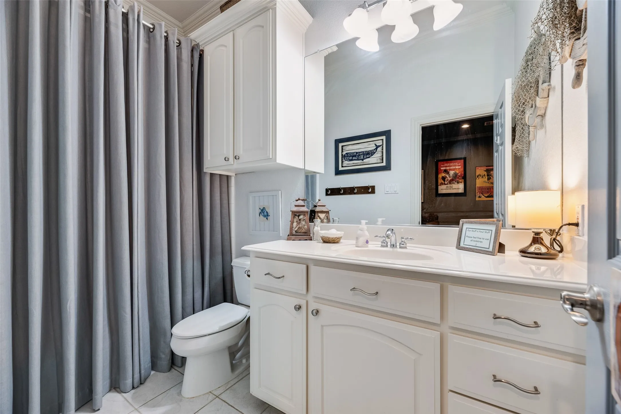 Bathroom featuring a white vanity with integrated sink, white cabinetry, and a large mirror