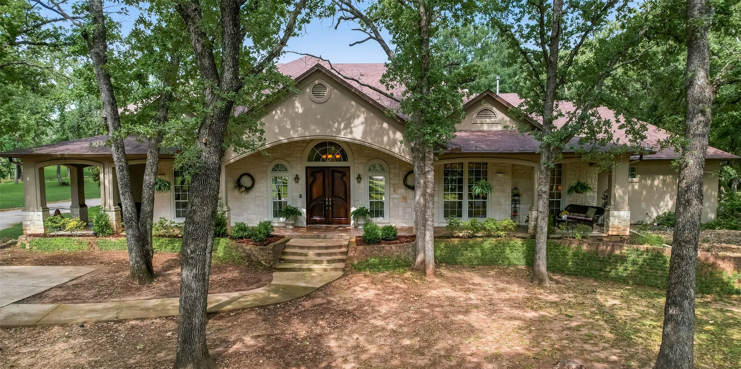 Stone and stucco exterior with a prominent arched entry, double wood entry doors, and a covered front porch featuring a porch swing