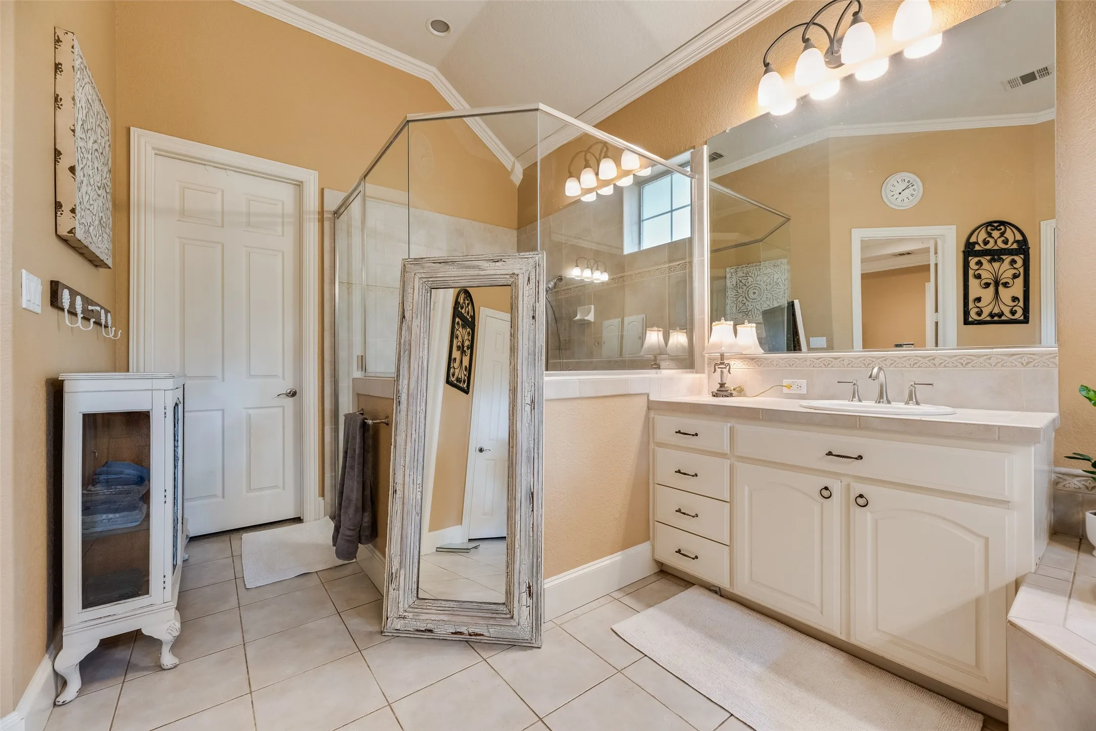 Bathroom featuring a glass-enclosed shower, single vanity with integrated sink, extensive countertop space, tile flooring, and a large mirror