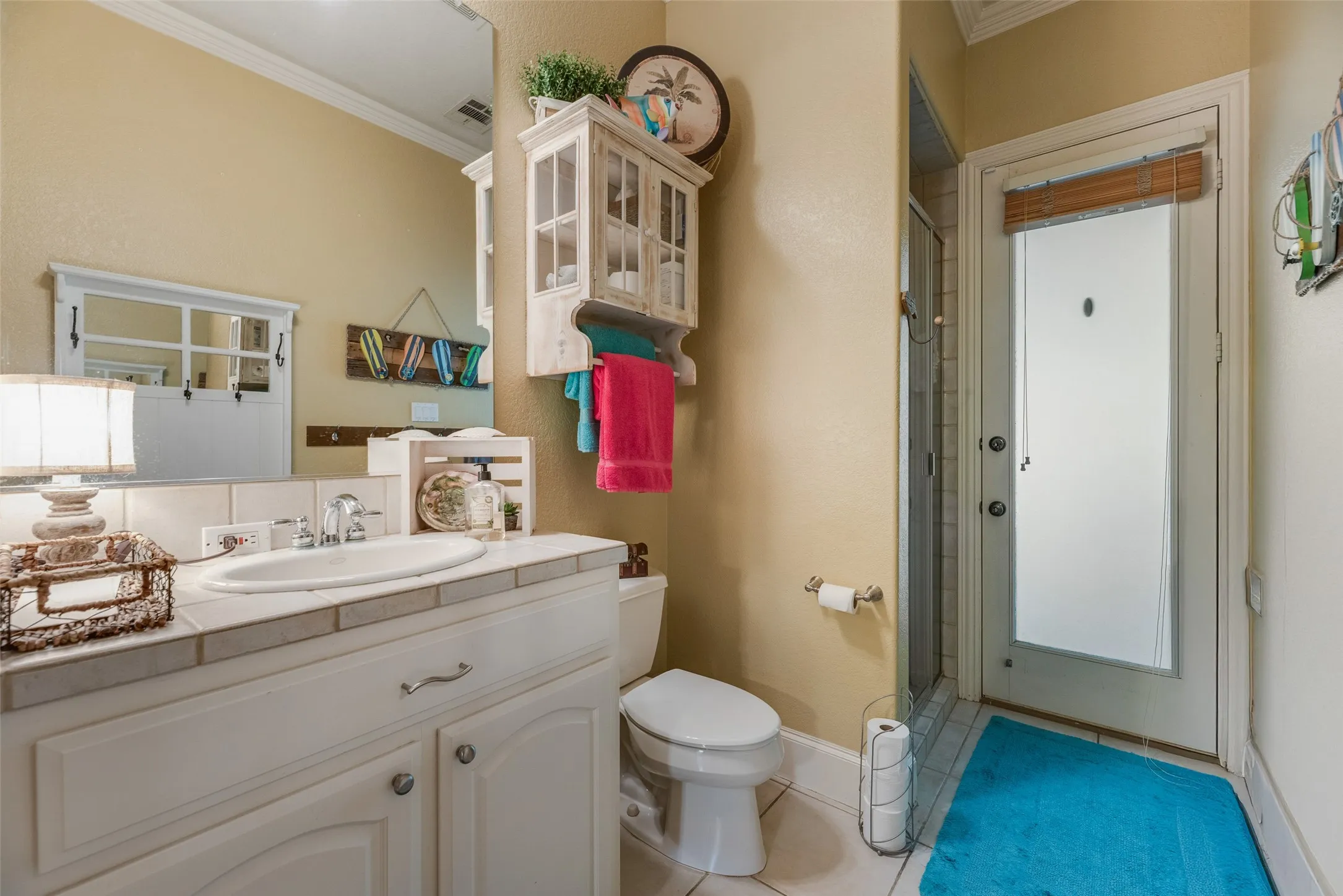 White vanity with an integrated sink, tile countertop, and chrome faucet