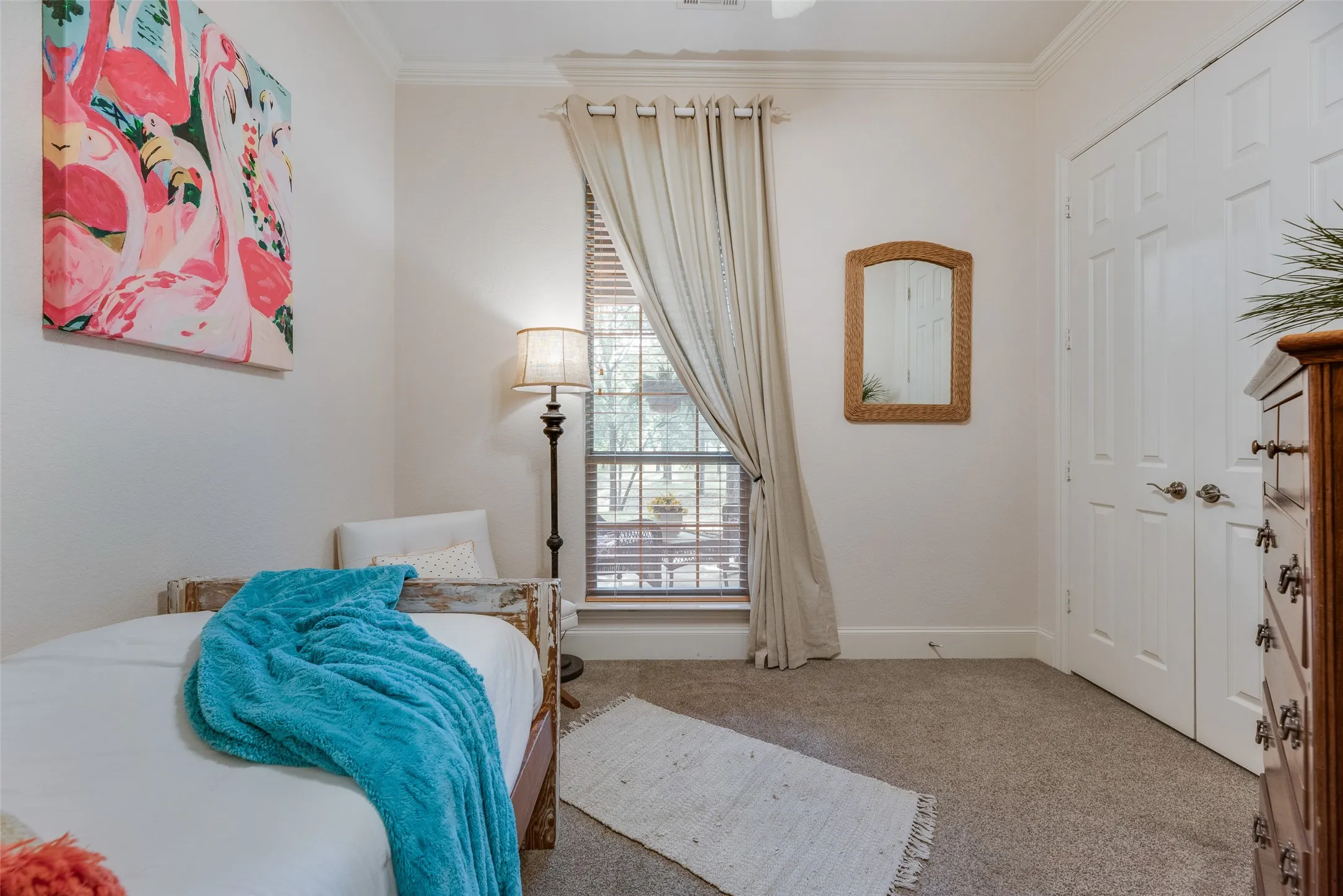 Natural light fills this space, featuring crown molding, a window with blinds, and white paneled bi-fold doors