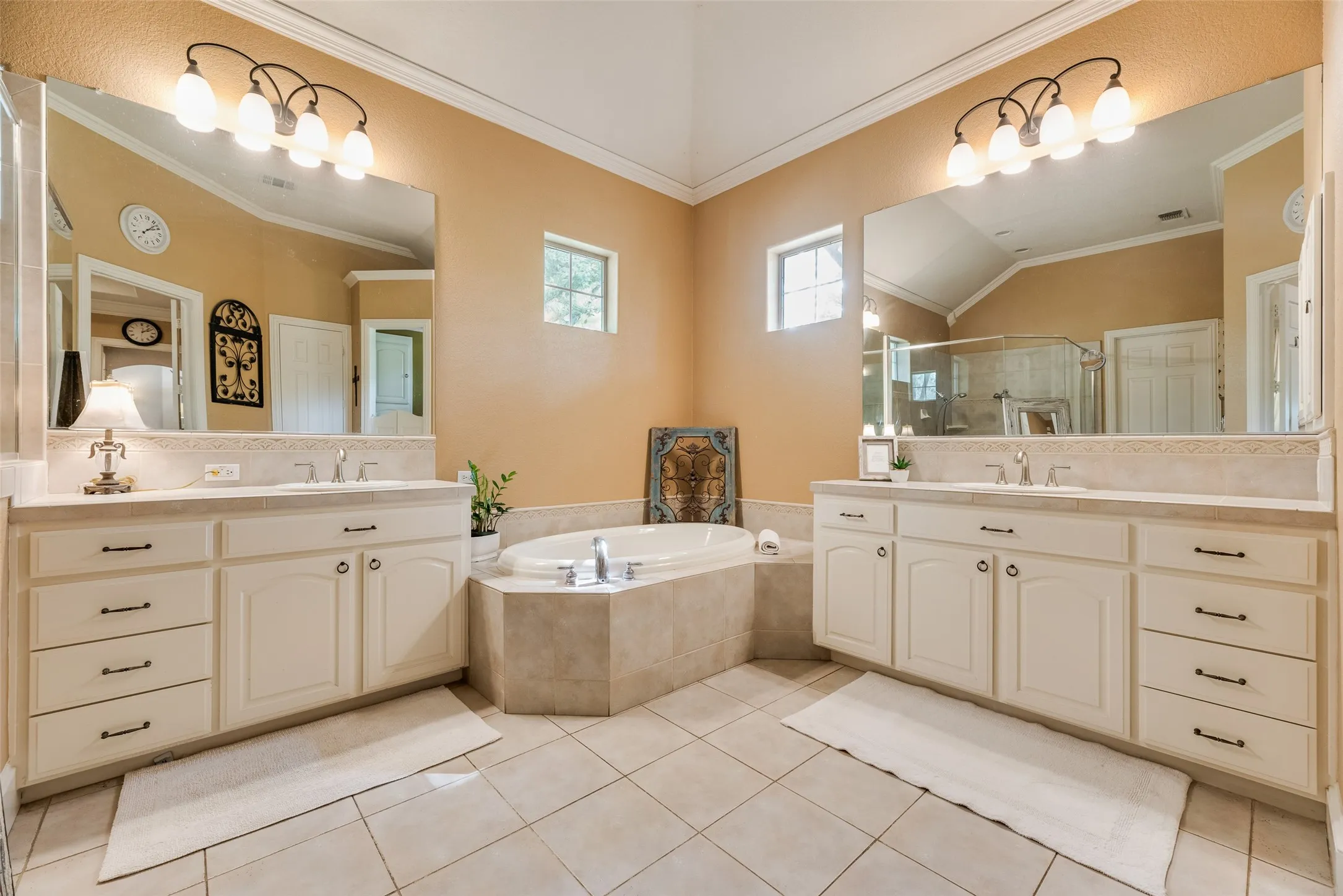 Bathroom featuring a corner soaking tub, dual vanity with undermount sinks, tile flooring, and a vaulted ceiling
