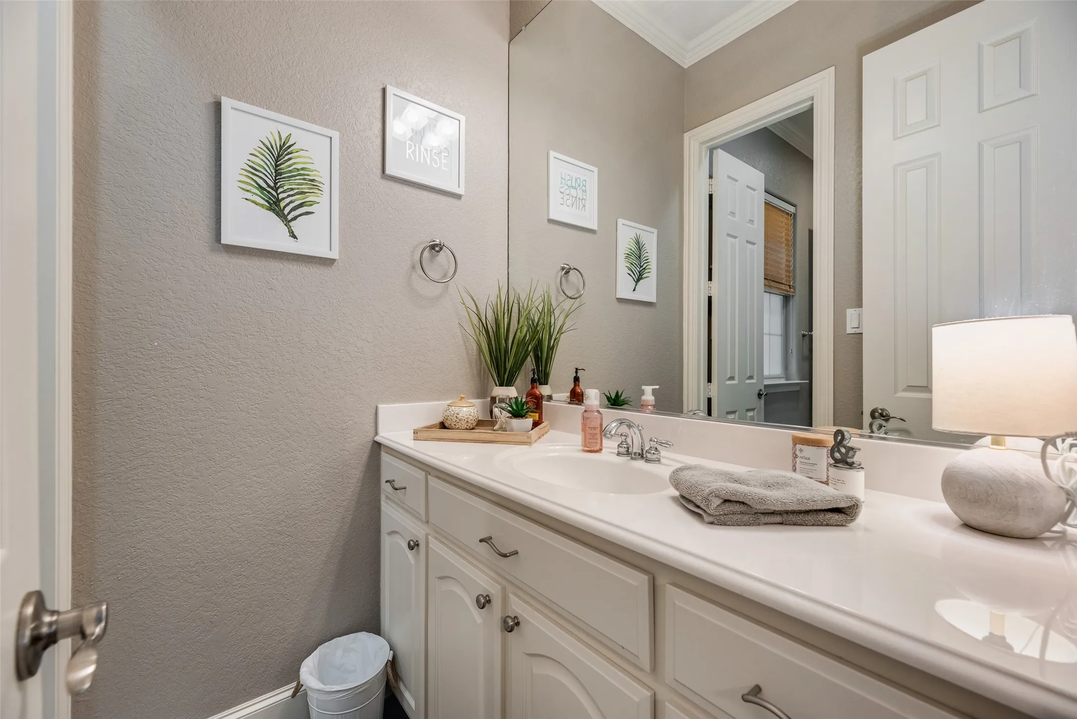 Bathroom vanity featuring an integrated sink, polished chrome faucet, and white cabinetry with silver-toned hardware